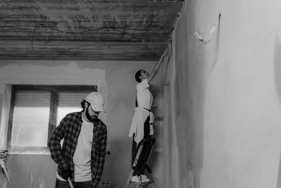 Black and white photo of a couple painting a room during home renovation.