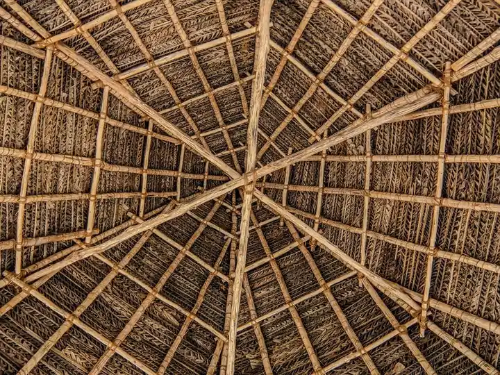 Close-up view of a traditional thatched roof with bamboo beams creating intricate patterns, Puducherry, India.
