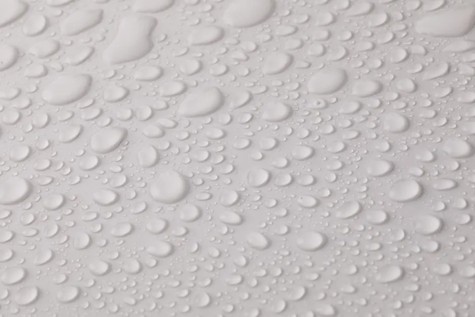 Closeup top view of plain wet abstract surface with small dripped water drops of different shapes placed on white background