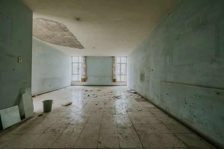 Explore an abandoned room with peeling paint and debris, showing decay.